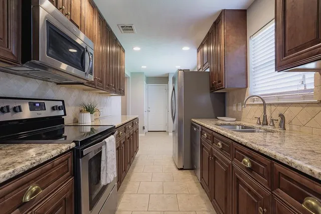 a kitchen with stainless steel appliances granite countertop a stove a sink and a refrigerator