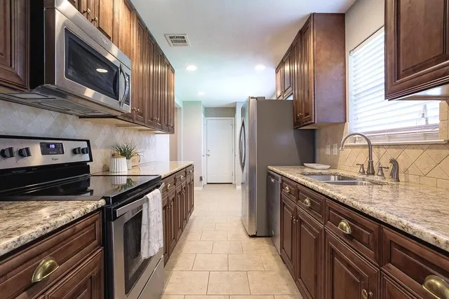 a kitchen with stainless steel appliances granite countertop a stove a sink and a refrigerator