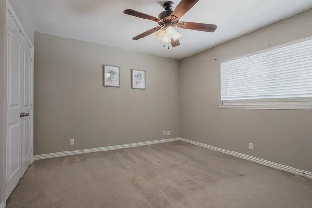 an empty room with a window and a fan