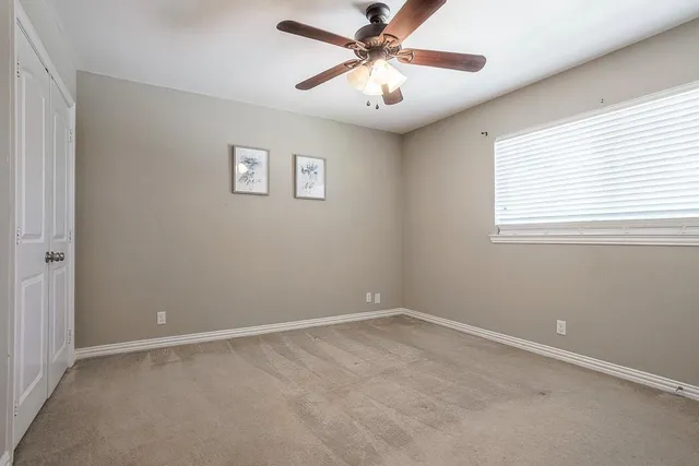 an empty room with a window and a fan