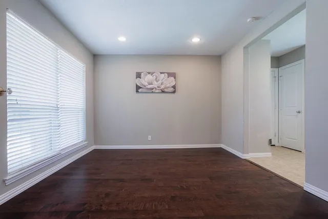 an empty room with wooden floor and window