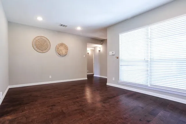 an empty room with a window and wooden floor