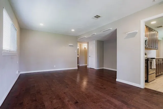 a view of an empty room with wooden floor and a window