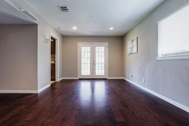 a view of an empty room with wooden floor and window