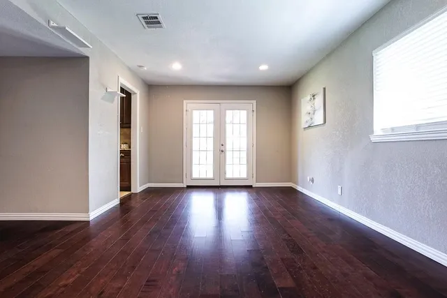 an empty room with wooden floor and windows
