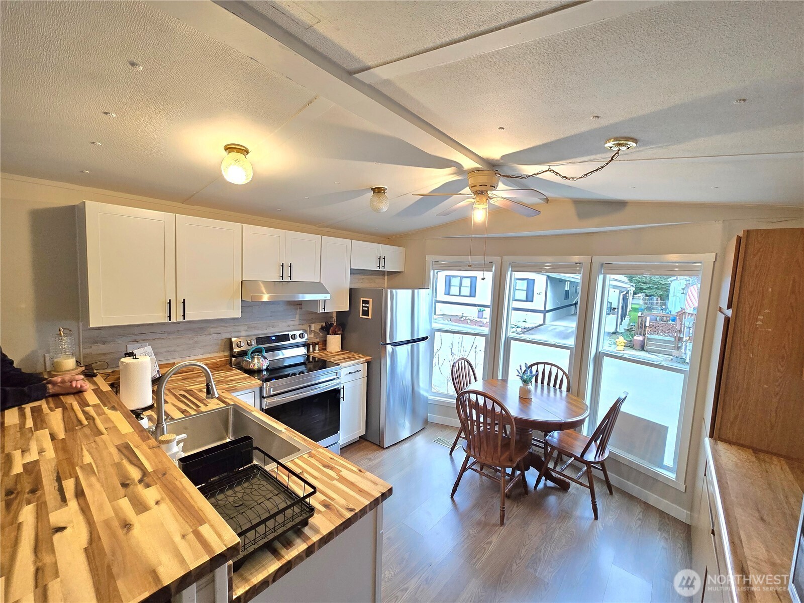 212 Old Owen Road, Unit 43 Sultan, WA 98294 - Photo 12 of 19 a kitchen with stainless steel appliances granite countertop a stove top oven a refrigerator a dining table and chairs with wooden floor