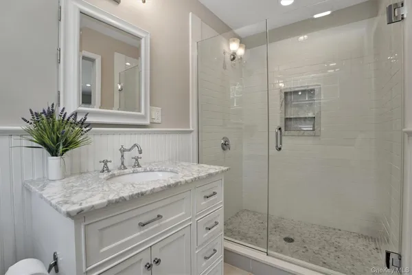 a bathroom with a granite countertop sink a mirror and a shower