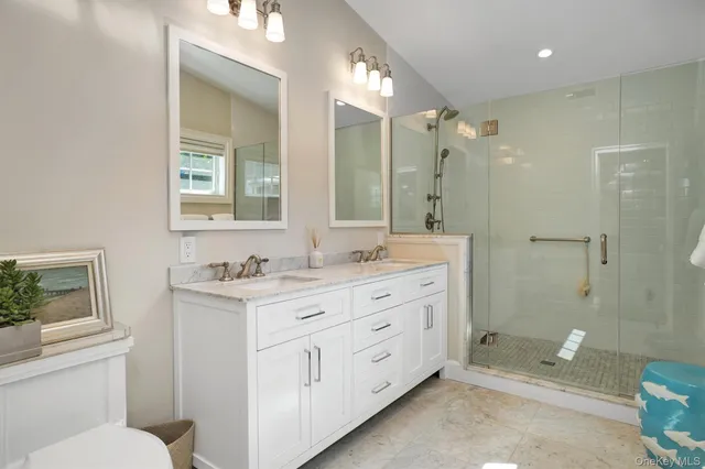 a bathroom with a double vanity sink toilet mirror and bathtub