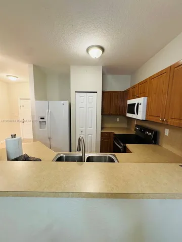 a kitchen with stainless steel appliances granite countertop a sink and a refrigerator