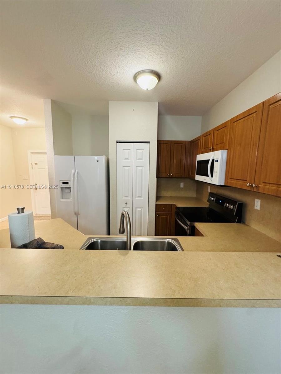 5753 Isles Circle Tamarac, FL 33321 - Photo 4 of 13 a kitchen with stainless steel appliances granite countertop a sink and a refrigerator