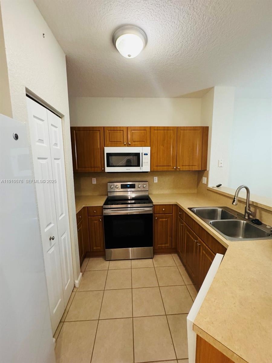 5753 Isles Circle Tamarac, FL 33321 - Photo 5 of 13 a kitchen with a sink a stove and refrigerator