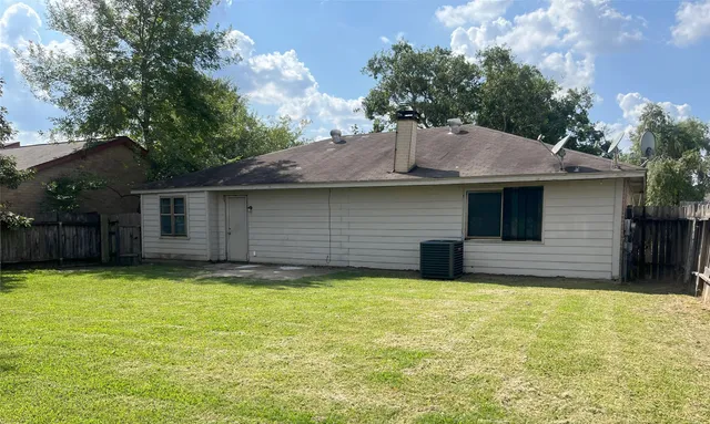 a view of a house with a yard and a large tree