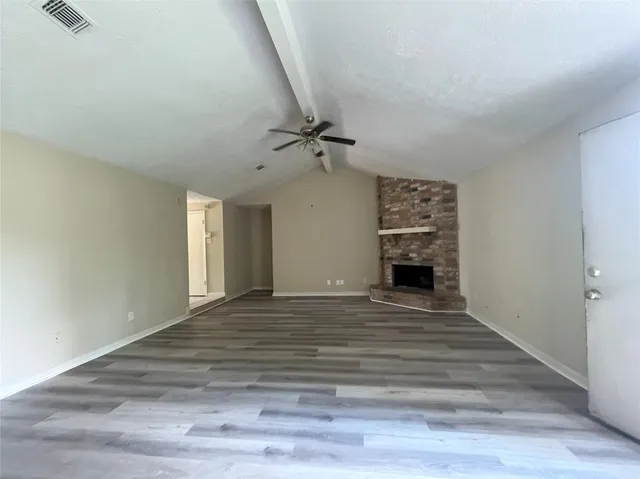 a view of a livingroom with a fireplace a ceiling fan and wooden floor