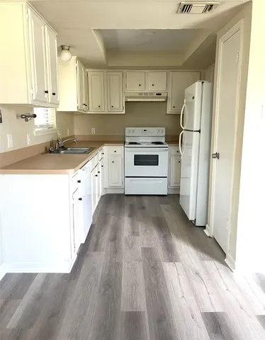a kitchen with a refrigerator a stove top oven and white cabinets