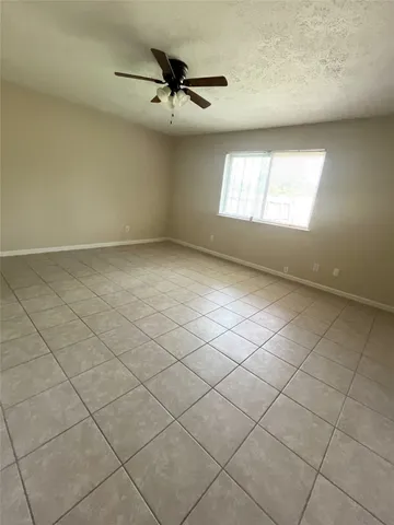 an empty room with windows and ceiling fan