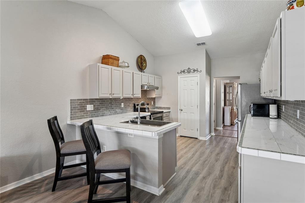 10318 Gifford Drive Spring Hill, FL 34608 - Photo 15 of 57 a kitchen with a table chairs refrigerator and a stove