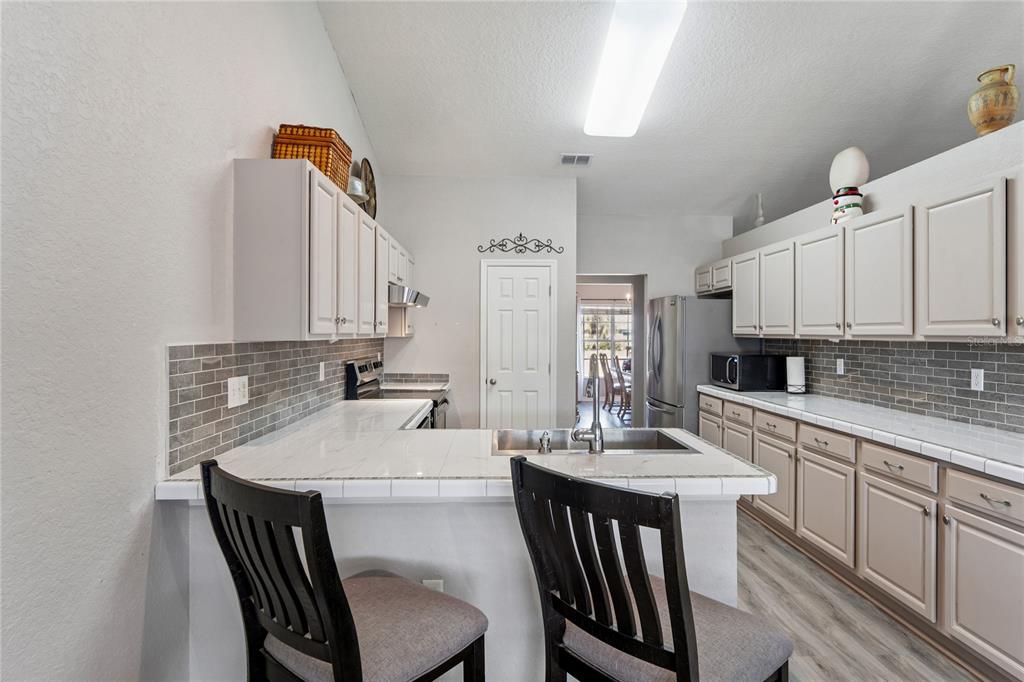 10318 Gifford Drive Spring Hill, FL 34608 - Photo 16 of 57 a kitchen with a dining table chairs and white cabinets