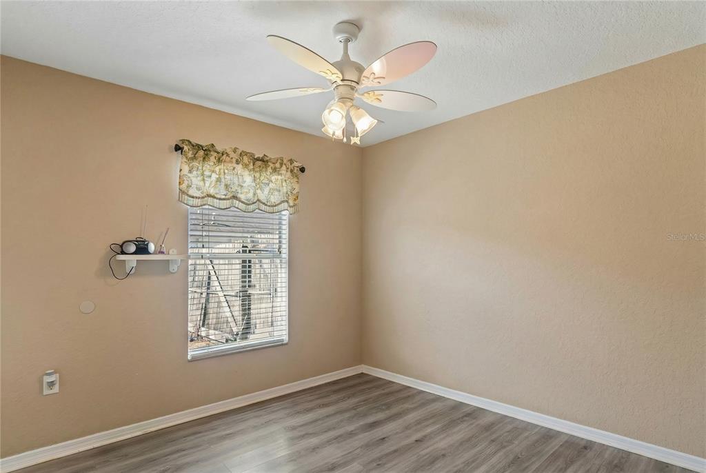 10318 Gifford Drive Spring Hill, FL 34608 - Photo 38 of 57 an empty room with wooden floor chandelier fan and windows