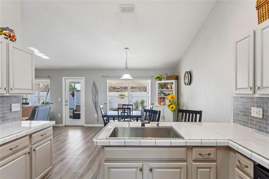 10318 Gifford Drive Spring Hill, FL 34608 - Photo 7 of 57 a kitchen with kitchen island granite countertop a sink dishwasher a dining table and chairs with wooden floor