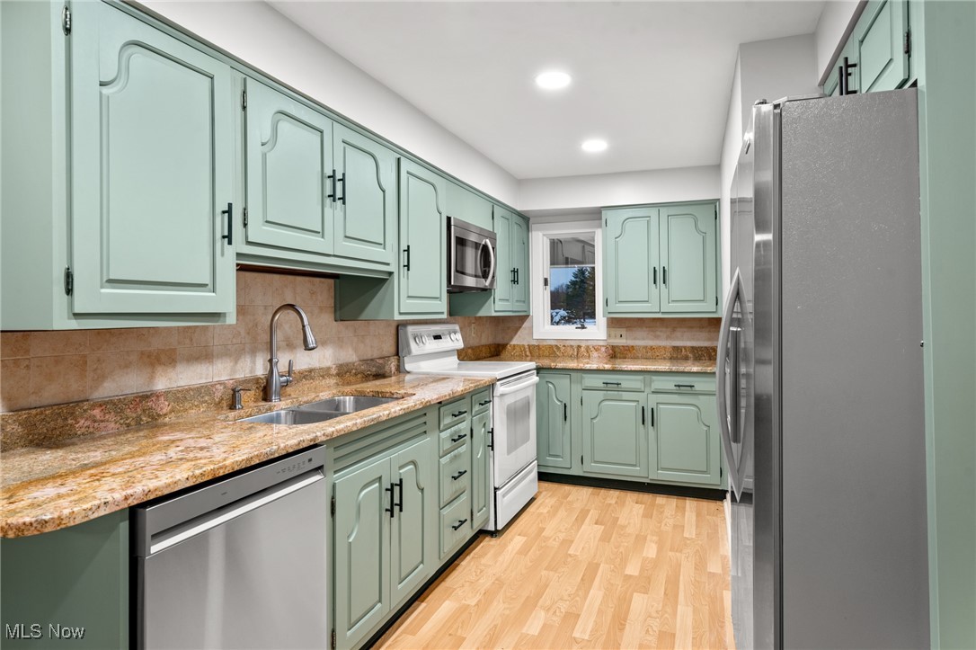 9513 Booth Road Willoughby, OH 44094 - Photo 23 of 45 Kitchen with green cabinets, sink, light hardwood / wood-style flooring, appliances with stainless steel finishes, and tasteful backsplash