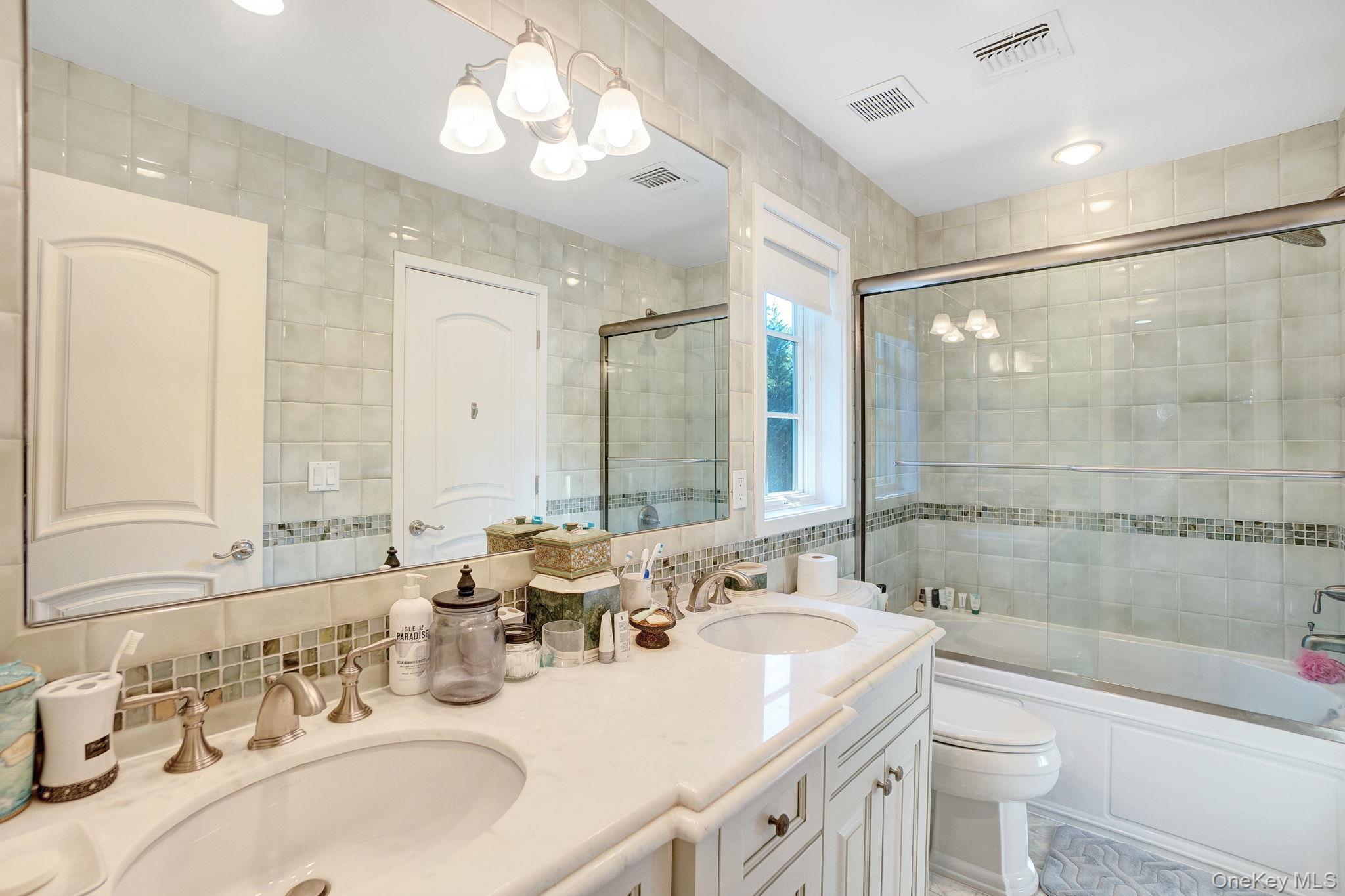 1 Norgate Road Glen Head, NY 11545 - Photo 30 of 42 a bathroom with double vanity sinks a toilet a mirror and shower