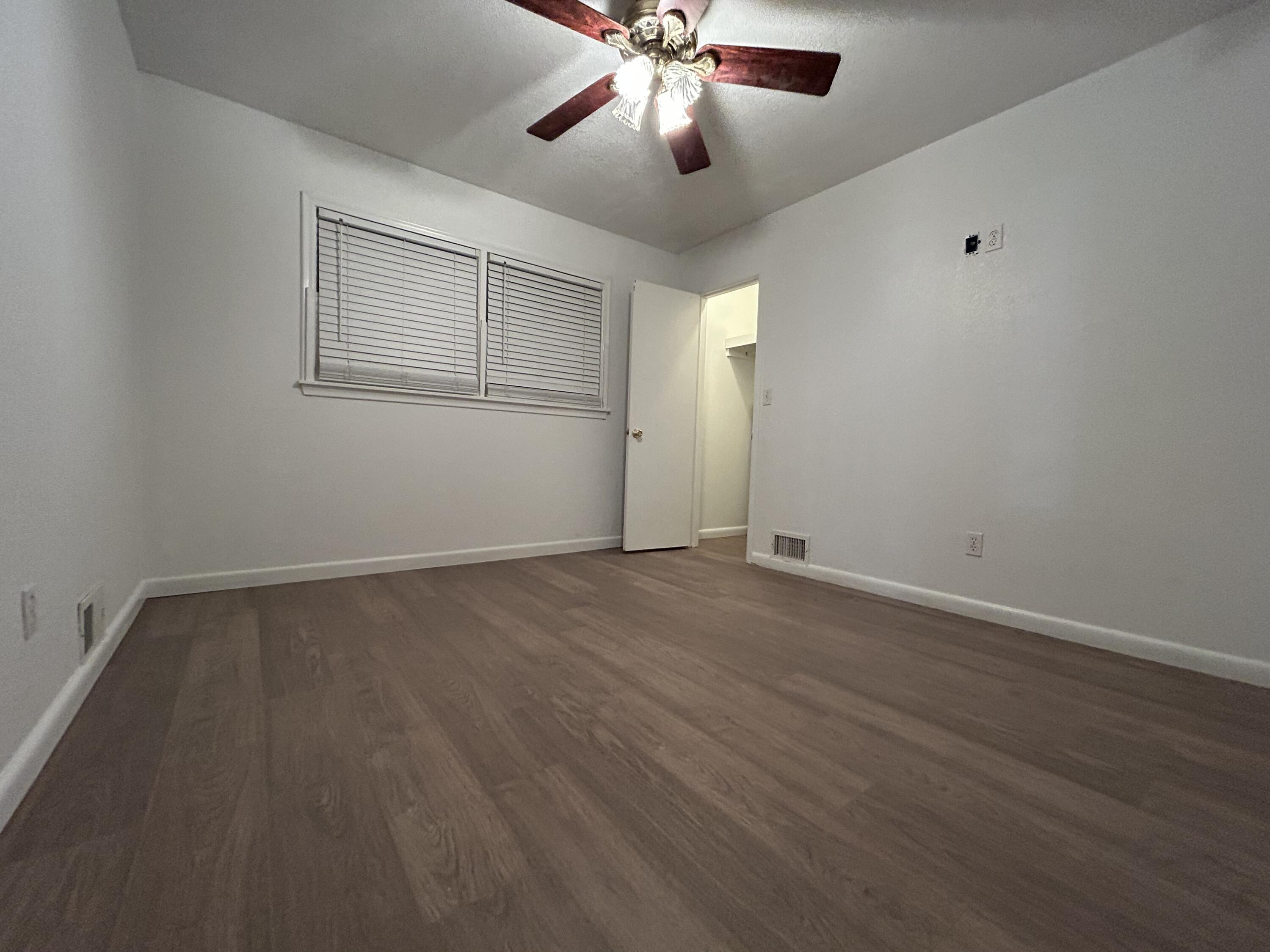 801 North 18th Street Lamesa, TX 79331 - Photo 11 of 15 an empty room with wooden floor ceiling fan and windows