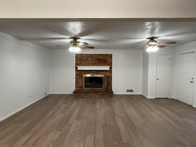 wooden floor in an empty room with a chandelier fan