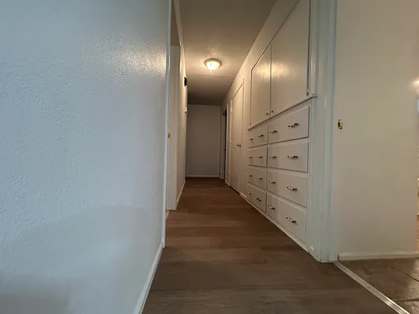 an empty room with wooden floor ceiling fan and windows