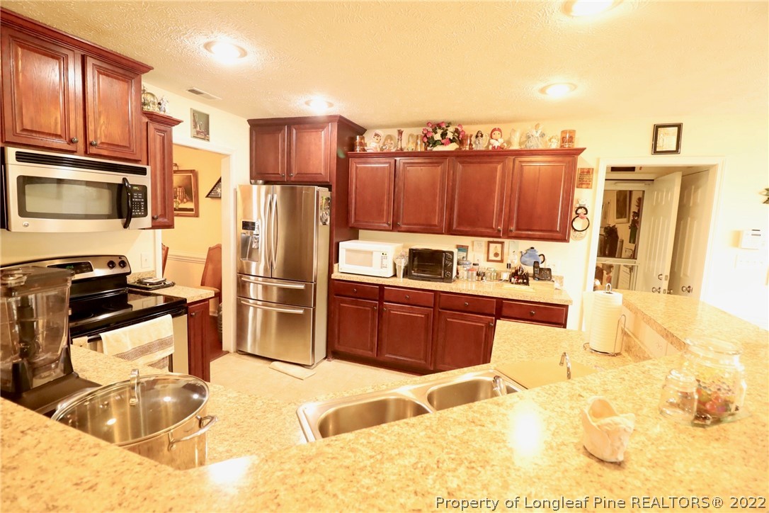 6087 Roebud Road Stedman, NC 28391 - Photo 24 of 31 a kitchen with stainless steel appliances kitchen island granite countertop a refrigerator stove and sink