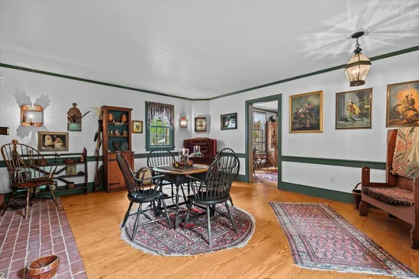 a living room with furniture a dining table and paintings on the wall with wooden floor