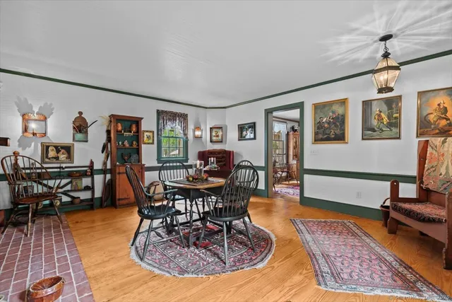 a living room with furniture a dining table and paintings on the wall with wooden floor