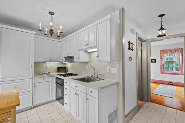 a kitchen that has a lot of white cabinets and stainless steel appliances
