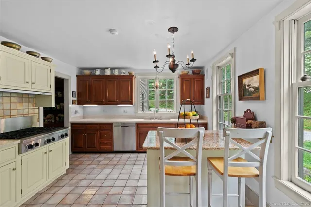 a kitchen with stainless steel appliances granite countertop a stove a sink dishwasher a dining table and chairs with wooden floor