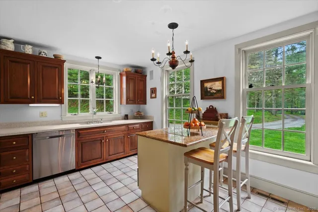 a dining hall with granite countertop a stove a sink dishwasher a dining table and chair with wooden floor