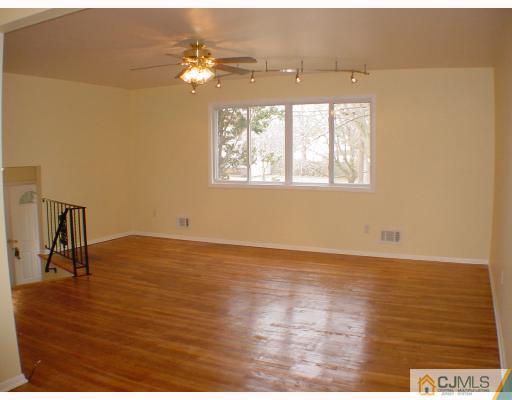 7 Barker Road Somerset, NJ 08873 - Photo 3 of 10 an empty room with wooden floor and fan
