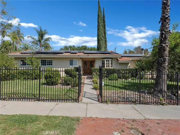 a backyard of a house with table and chairs plants and large tree