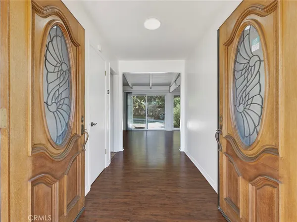 a view of an empty room with window and chandelier fan