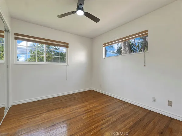 a view of an empty room with wooden floor and a fireplace