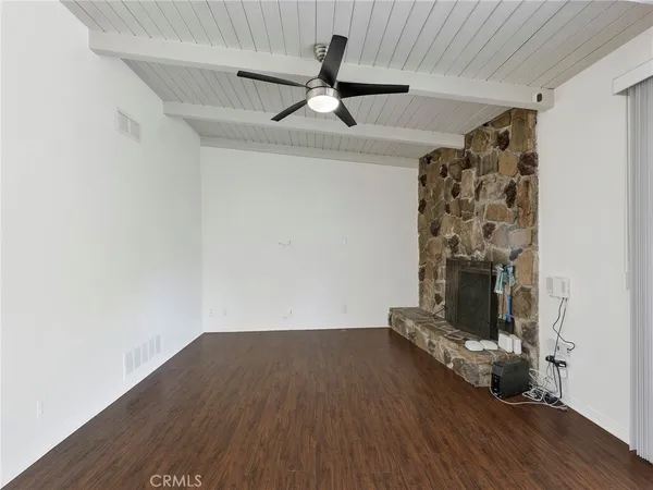 a view of an empty room with wooden floor and a ceiling fan