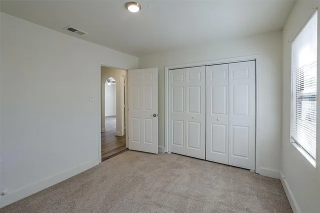 an empty room with windows and closet area