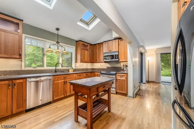 a kitchen with granite countertop a stove a sink a refrigerator and wooden floor