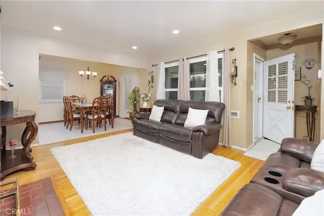 a living room with furniture and a dining table with wooden floor