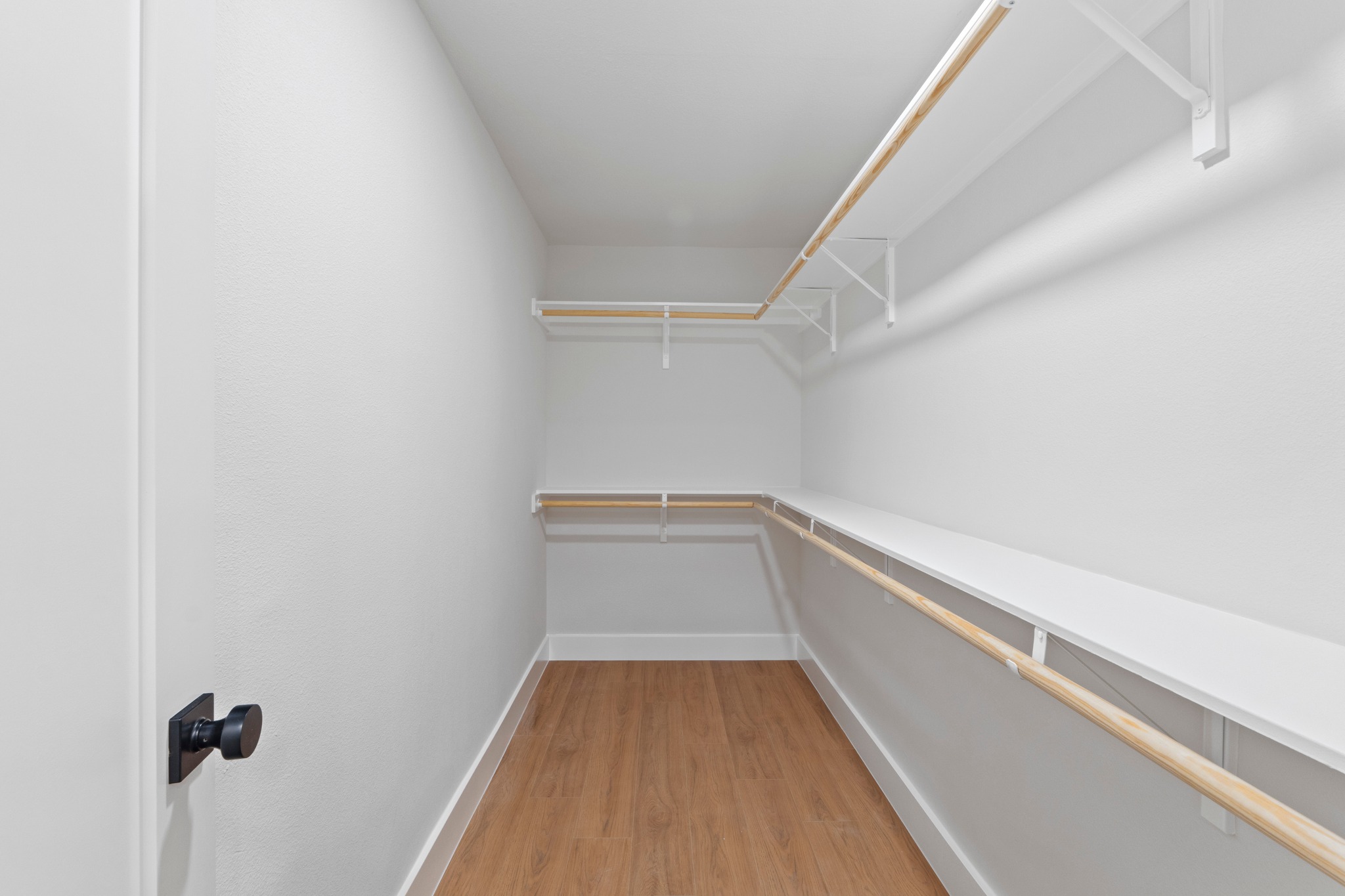 1608 Springer Lane Austin, TX 78758 - Photo 17 of 35 Walk-in closet featuring wood-finish flooring, white walls, and built-in white shelving with wood rods