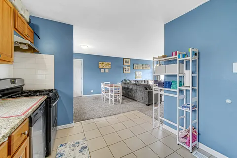 a kitchen with stainless steel appliances granite countertop a stove top oven a sink a dining table and chairs