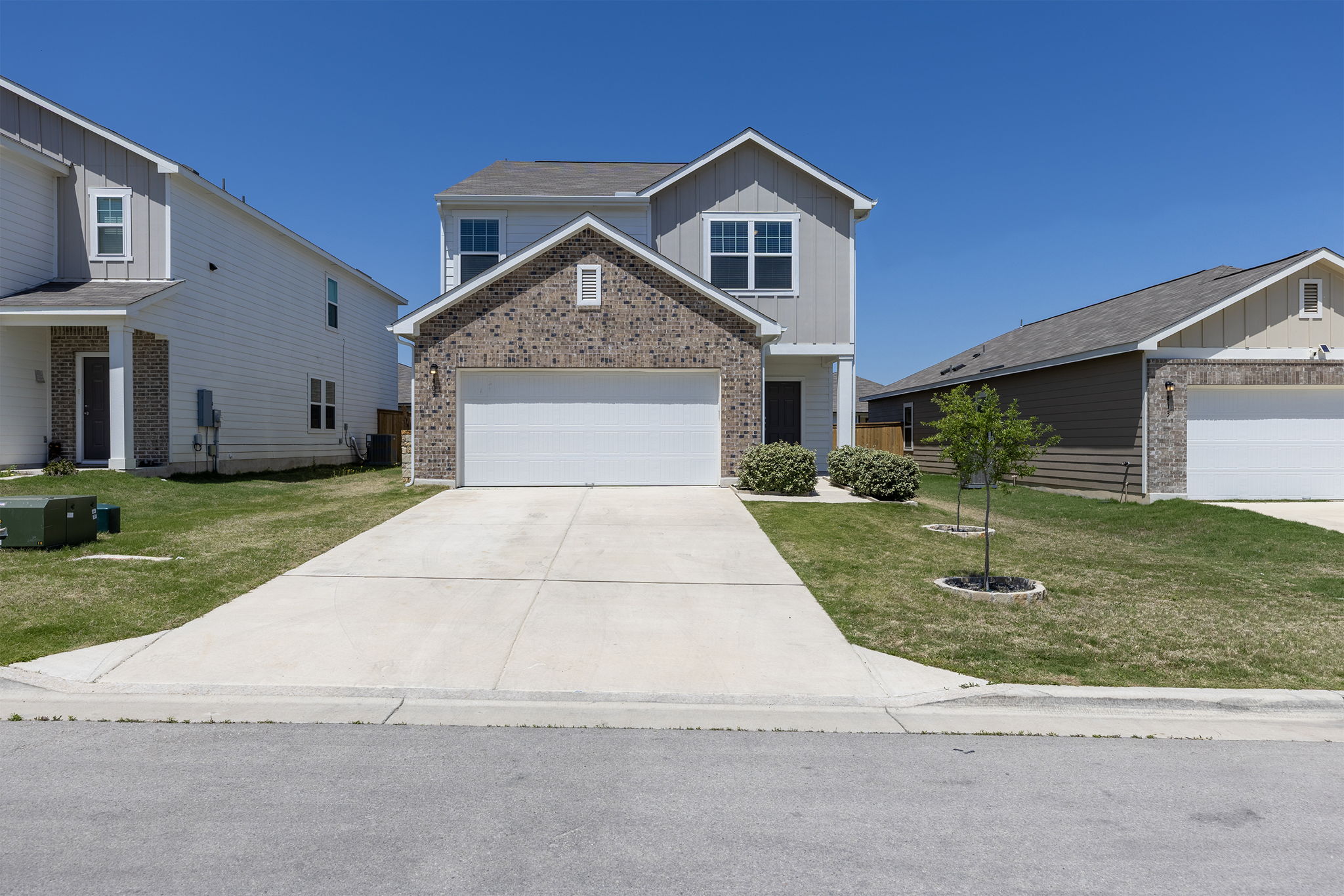 409 Line Of Fire Way Jarrell, TX 76537 - Photo 1 of 30 Two-story residence featuring a brick façade accent, horizontal and vertical siding, attached two-car garage, concrete driveway, covered front entry, and front yard landscaping.