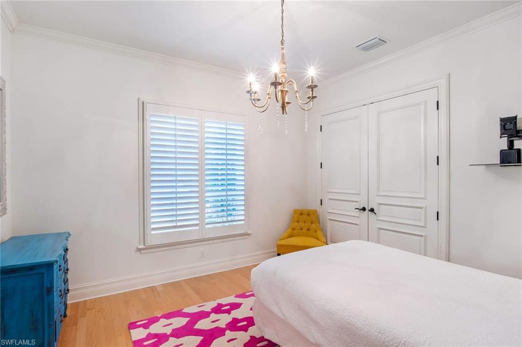 516 Portside Drive Naples, FL 34103 - Photo 21 of 25 a bedroom with a bed chandelier and a window