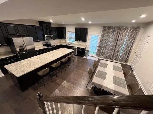 a living room with stainless steel appliances kitchen island granite countertop furniture a rug and a kitchen view