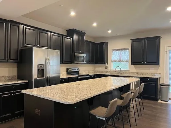 a kitchen with granite countertop a center island stainless steel appliances and cabinets