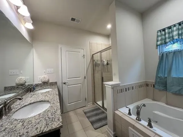 a bathroom with a granite countertop tub sink and mirror