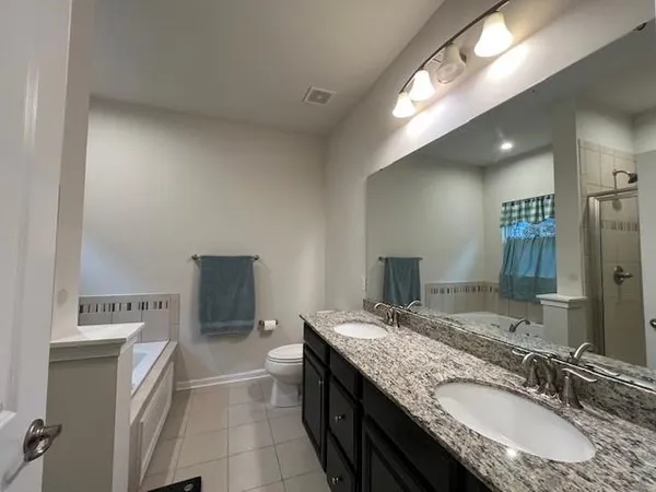 a bathroom with a granite countertop sink a mirror and a toilet